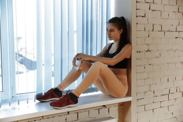 Relaxar após o treino. Mulher bonita olhando para longe, enquanto sentado no ginásio — Fotografia de Stock