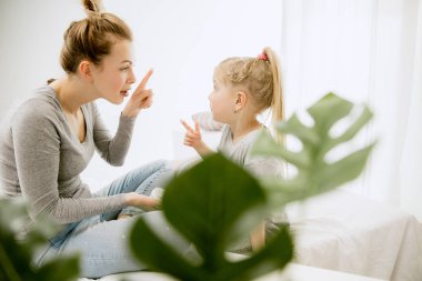 Genç anne ve küçük kızı sarılma ve yatakta öpüşme
