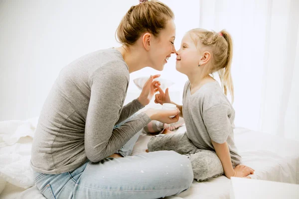 Jeune mère et sa petite fille embrassant et embrassant sur le lit — Photo