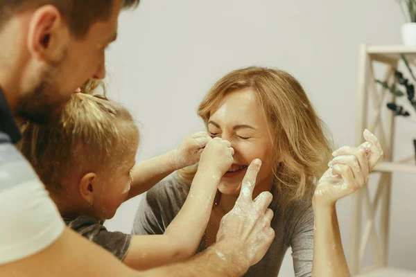 Menina bonito e seus belos pais preparando a massa para o bolo na cozinha em casa — Fotografia de Stock