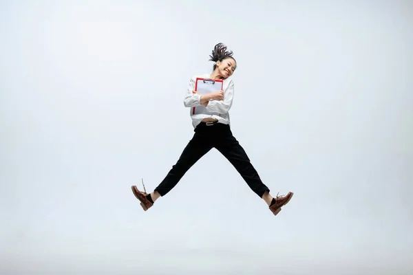 Женщина, работающая в офисе и прыгающая изолированно на фоне студии — стоковое фото