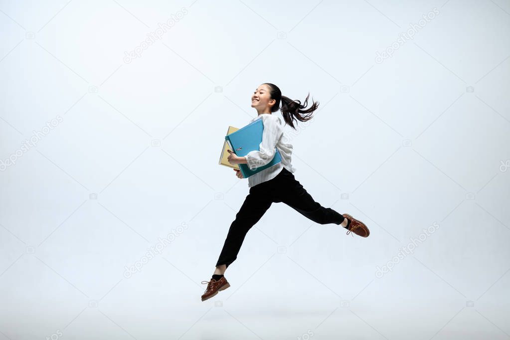 Woman working at office and jumping isolated on studio background
