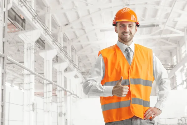 O construtor em capacete laranja contra fundo industrial — Fotografia de Stock