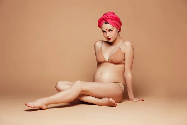 Wanita hamil muda berpose dengan latar belakang coklat — Stok Foto