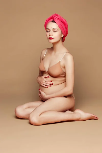 Young beautiful pregnant woman posing on brown background — Stock Photo, Image