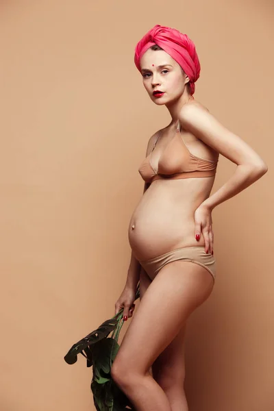 Молодая красивая беременная женщина позирует на коричневом фоне — стоковое фото