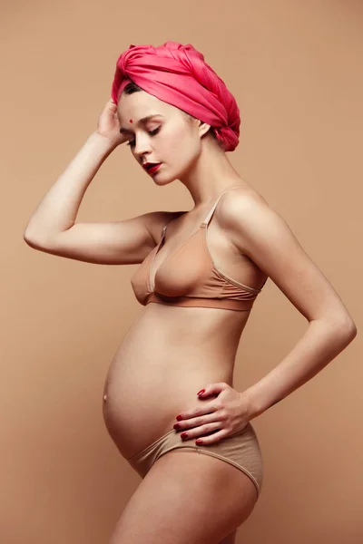 Jonge mooie zwangere vrouw poseren op bruine achtergrond — Stockfoto