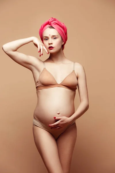 年轻美丽的孕妇摆姿势在棕色背景 — 图库照片
