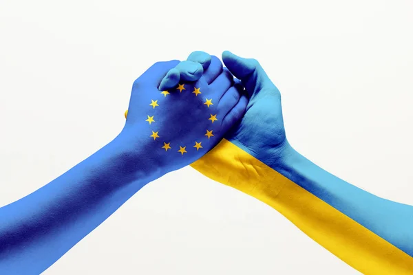 Två händer. Europeiska unionens flagga. Ukrainas flagga. — Stockfoto