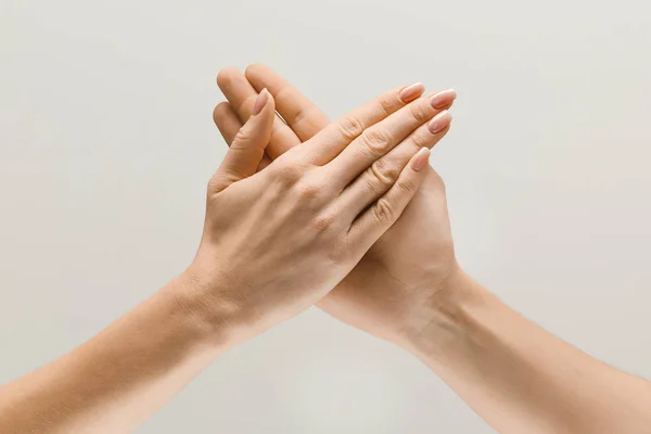 Male and female hands demonstrating a gesture of getting touch isolated on gray background