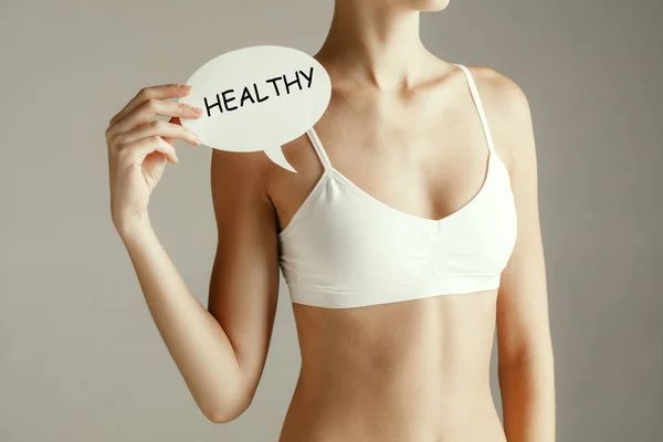 Young adult woman holding paper card with word HEALTHY. — Stock Photo, Image