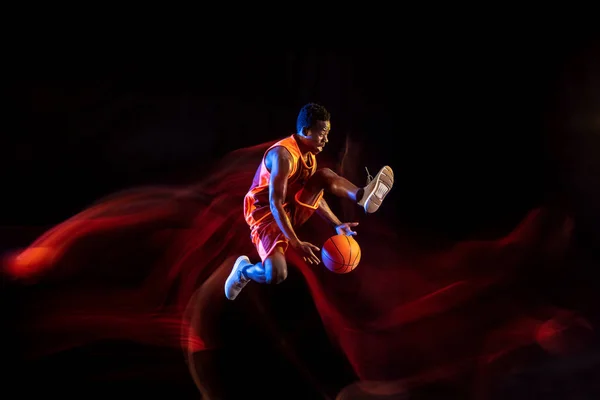 Jovem jogador de basquete contra fundo escuro — Fotografia de Stock