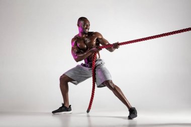 Genç Afro-Amerikan vücut geliştirme eğitimi gri arka planda