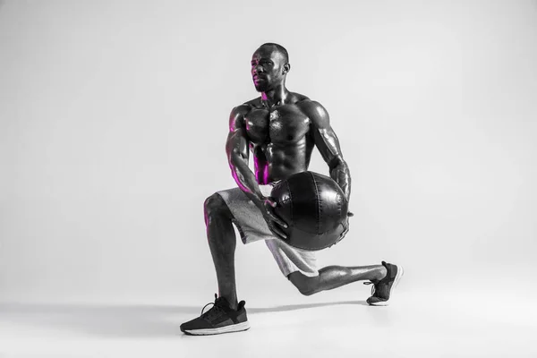 Jonge Afrikaans-Amerikaanse bodybuilder training over grijze achtergrond — Stockfoto