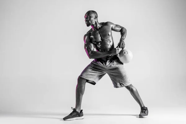 Treinamento de fisiculturista afro-americano jovem sobre fundo cinza — Fotografia de Stock