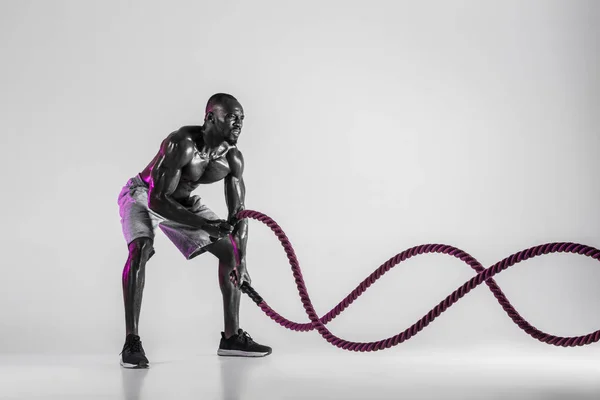 Junger afrikanisch-amerikanischer Bodybuilder beim Training vor grauem Hintergrund — Stockfoto