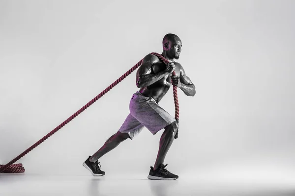 Młody afrykańsko-amerykański kulturysta trening na szarym tle — Zdjęcie stockowe