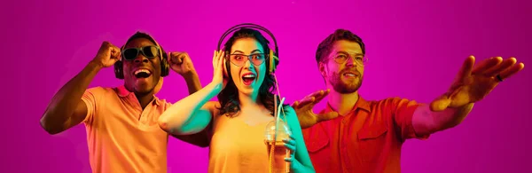 Hermosos jóvenes en luz de neón aislados en el fondo del estudio rosa —  Fotos de Stock