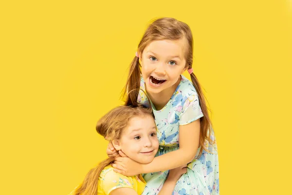 Schöne emotionale kleine Mädchen isoliert auf gelbem Hintergrund — Stockfoto