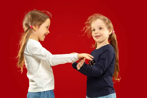 Красивые эмоциональные маленькие девочки изолированы на красном фоне — стоковое фото