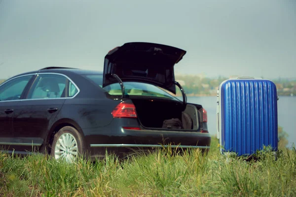 Blick auf modernes schwarzes Auto und Koffer auf der Flussseite — Stockfoto
