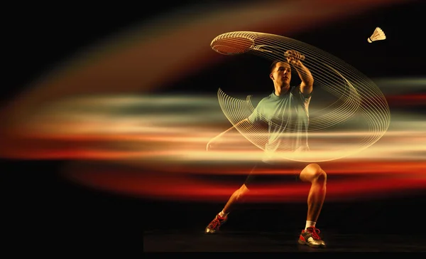 Młody człowiek gra badmintona na ciemnym tle — Zdjęcie stockowe