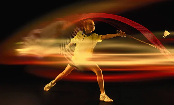 Young girl playing badminton over dark background — 스톡 사진