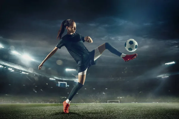 Футболистка пинает мяч на стадионе — стоковое фото
