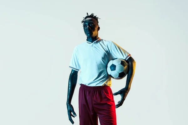 Male soccer player standing with the ball isolated on white background