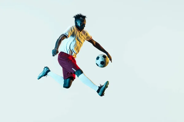 Męski piłkarz kopiąc piłkę na białym tle — Zdjęcie stockowe