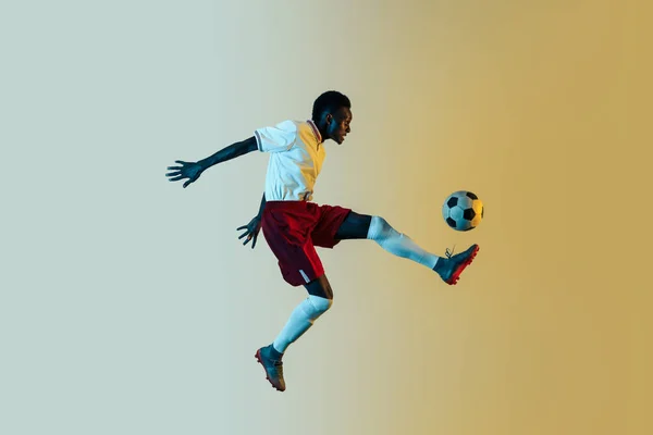 Male soccer player kicking ball in jump isolated on gradient background — Stock Photo, Image