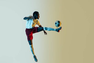 Erkek futbolcu degrade arka planda izole atlama topu tekme