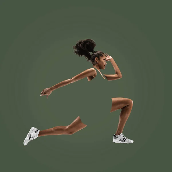 Junge Afrikanerin läuft oder joggt isoliert auf grünem Studiohintergrund. — Stockfoto