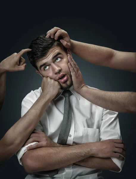 A young man surrounded by hands like his own thoughts