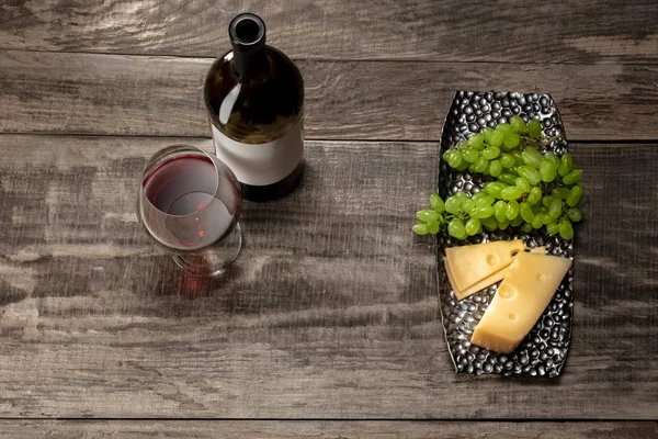 Uma garrafa e um copo de vinho tinto com frutas sobre fundo de madeira — Fotografia de Stock