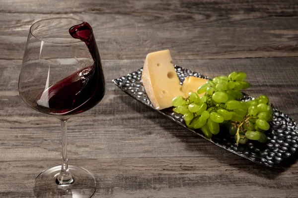 Una bottiglia e un bicchiere di vino rosso con frutta su sfondo di legno — Foto Stock
