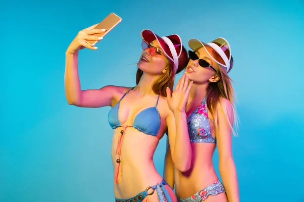 Hermosas chicas aisladas en el fondo del estudio azul en luz de neón — Foto de Stock