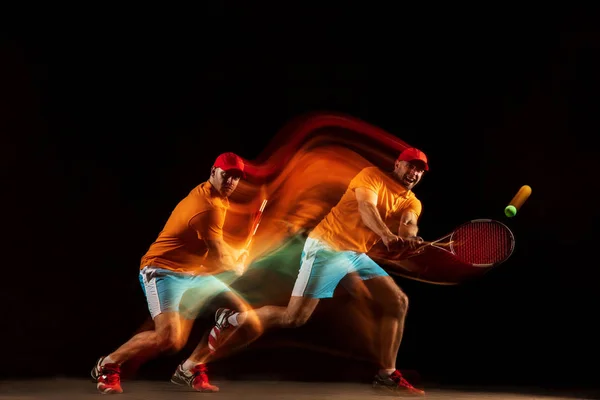 Один кавказский человек играет в теннис на черном фоне — стоковое фото