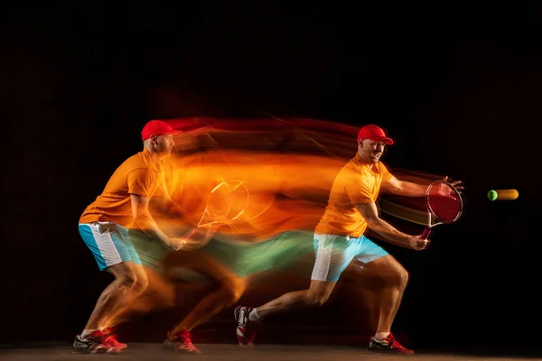 Seorang pria Kaukasia bermain tenis di latar belakang hitam — Stok Foto