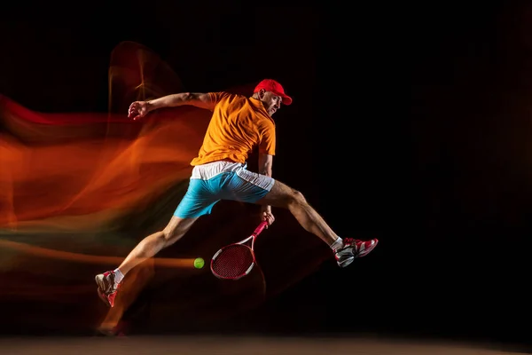 Один кавказский человек играет в теннис на черном фоне — стоковое фото
