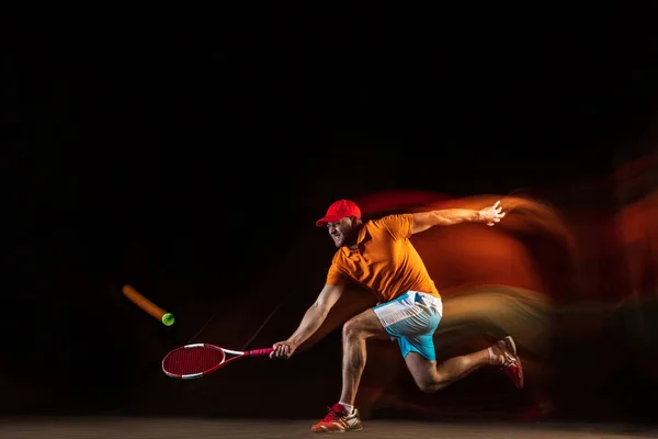 En kaukasisk man spelar tennis på svart bakgrund — Stockfoto