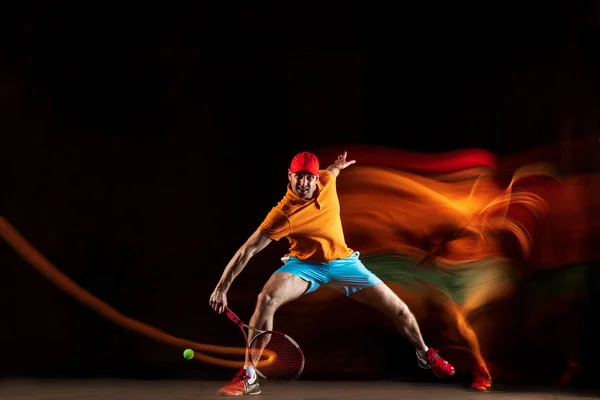 Um homem caucasiano jogando tênis no fundo preto — Fotografia de Stock
