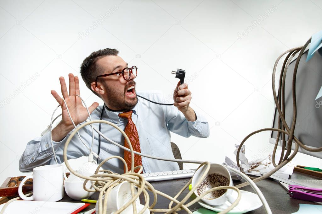 Young man tangled in wires on the workplace