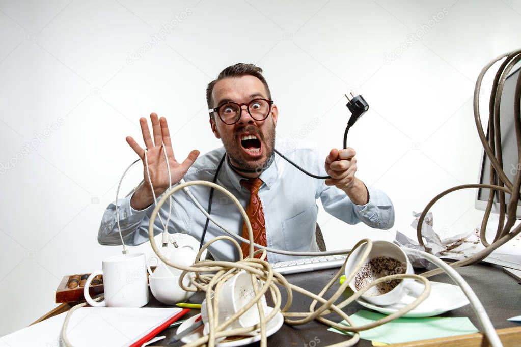 Young man tangled in wires on the workplace