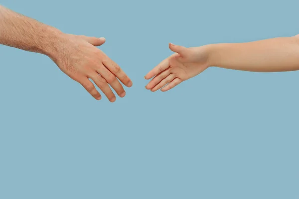 Closeup shot of human holding hands isolated on blue studio background.