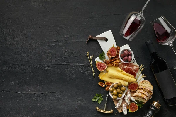 Due bicchieri di vino rosso e piatto di formaggio con frutta sulla pietra nera — Foto Stock