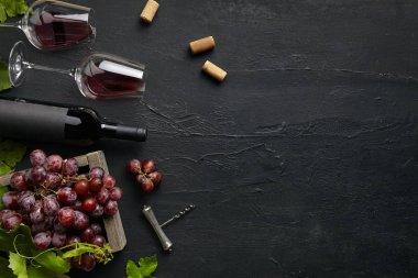 Siyah taş üzerinde şarap şişesi ile lezzetli meyve tabağı üst görünümü