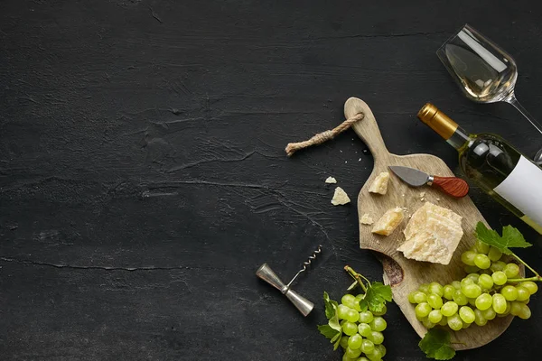 Dois copos de vinho branco e um prato de queijo saboroso em uma placa de cozinha de madeira . — Fotografia de Stock