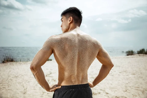 Młody człowiek zdrowy zawodnik robi przysiady na plaży — Zdjęcie stockowe