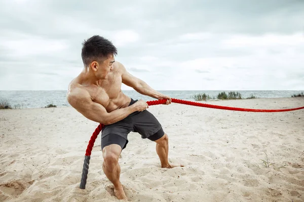 Ung frisk man idrottsman gör knäböj på stranden — Stockfoto